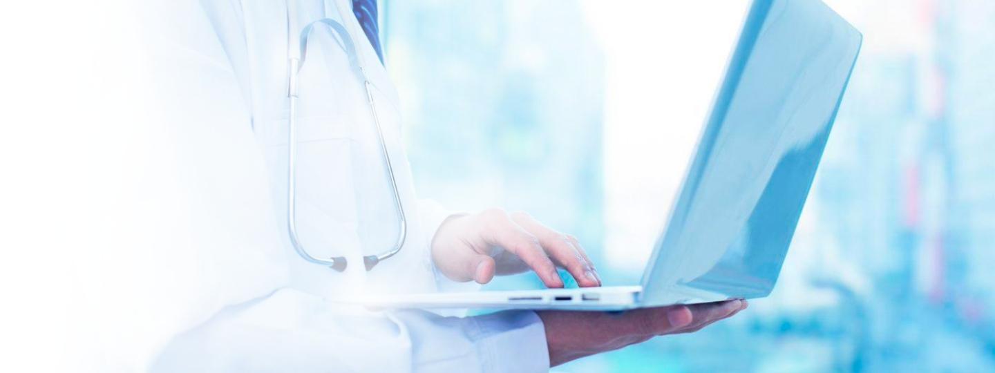 Close-up of healthcare professional’s hands on laptop